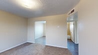 This single-story unit offers an efficient and functional layout, accommodating three bedrooms, one full bathroom, a kitchen, a hallway, and two closets within a compact footprint. The interior features a neutral, warm color palette with beige walls and white trim that creates a clean, cohesive look throughout.

The bedrooms are carpeted and simply appointed, with textured ceilings and flush-mount light fixtures. The primary bedroom is a comfortable size and connects to an adjacent room, with the shared bathroom conveniently accessible nearby. The additional bedrooms each feature windows that invite natural light, and one includes a closet with a classic six-panel door.

The kitchen is outfitted with dark wood cabinetry, a sink, and a refrigerator, and features durable hardwood-style flooring. A window over the dining area brings in natural light, adding brightness to the space.

The bathroom is tiled in a warm beige tone from floor to ceiling in the shower surround, and includes a combination tub and shower with a window for ventilation and light.

Throughout the unit, HVAC vents are integrated into the ceilings and walls, ensuring climate control in each room. The hallway connects the main living areas efficiently, making the overall layout practical and easy to navigate.