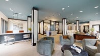 Located at 1924 Monroe Dr NE in Atlanta's vibrant 30324 corridor, this single-floor space offers a generously sized, well-appointed layout designed with both comfort and function in mind. The two living areas are defined by teal-painted ceilings, light hardwood flooring, bold black-framed columns, and expansive floor-to-ceiling windows that flood the interior with natural light and frame views of mature surrounding trees. One lounge area features a built-in wet bar with a beverage refrigerator and glass-enclosed accent wall, while the other provides an inviting seating arrangement with multiple conversation zones. The two private office spaces are thoughtfully furnished, each offering a sleek dark desk, an ergonomic accent chair, patterned area rugs, and framed artwork—ideal for focused, individual work. A central corridor connects the rooms, with a built-in workspace visible along one hallway wall. The two bathrooms are a design highlight, clad floor-to-ceiling in rich teal vertical subway tiles complemented by bold black-and-white geometric patterned floor tiles, wall-mounted sinks, and matte black fixtures. Recessed lighting throughout ensures consistent, refined illumination across the entire space, creating a polished and contemporary ambiance from end to end.