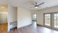 Located at 1120 Corner Wind Ln in Columbia, SC, this single-floor, 2-bedroom, 2-bathroom home offers a clean, modern aesthetic throughout. The open-concept kitchen and living area serves as the heart of the home, showcasing a large granite island with an undermount sink, stainless steel appliances including a French door refrigerator, electric range, microwave, and dishwasher. White upper cabinets are paired with sage-toned lower cabinets, complemented by a classic white subway tile backsplash. Pendant lighting and recessed fixtures add a polished touch. The living area features hardwood-style flooring and French doors that open to an outdoor view, filling the space with natural light. The bedrooms are bright and well-proportioned, with large windows, neutral walls, and the same warm hardwood-style flooring. Both bathrooms are finished with white subway tile tub-surround enclosures, and one bathroom features a gray vanity with granite countertops. A dedicated laundry room with a full-size washer and dryer adds everyday convenience. Two closets provide ample storage throughout. The overall design is cohesive and contemporary, with neutral tones and quality finishes creating a comfortable and functional living environment.