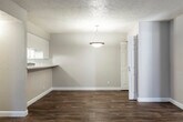 This single-floor residence offers a thoughtfully laid-out living space with a mix of durable hardwood-style flooring in the main areas and plush carpeting in the bedrooms. The kitchen is well-equipped with white cabinetry, light-toned countertops, a gas range, stainless steel dishwasher, and an overhead ventilation hood. A pass-through counter connects the kitchen to the adjacent dining area, which features a pendant light fixture and flows seamlessly into the living room. The living room benefits from natural light streaming through large sliding glass doors fitted with vertical blinds, offering access to an outdoor space. The bedrooms are comfortably sized, each featuring soft carpeting, ample closet space with sliding doors, and windows that bring in natural light. The bathrooms are clean and functional, each outfitted with a tub-shower combination, white cabinetry, light stone-patterned countertops, and wood-style flooring. Throughout the residence, textured ceilings, neutral wall tones, and crisp white trim create a cohesive and understated aesthetic. Centralized HVAC vents ensure consistent climate control throughout the home.