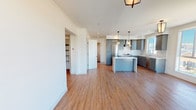 This single-floor residence is thoughtfully designed with a clean, modern aesthetic carried throughout. The open-concept layout connects the living area to a well-appointed kitchen, creating a spacious and cohesive common area. Warm wood-look flooring runs continuously through the main living spaces, complementing the bright white walls and recessed lighting overhead.

The kitchen is a standout feature, showcasing gray shaker-style cabinetry with brushed gold hardware, striking quartz countertops with marble-like veining, and a matching full-height backsplash. A central island provides additional prep and seating space, while pendant lighting adds a refined touch. Stainless steel appliances, including a gas range with a dedicated hood and a dishwasher, complete the culinary setup.

The bedrooms offer a calm, neutral palette with wood-look flooring and walk-in closet space. Natural light enters through well-positioned windows, and one room connects to a private balcony through sliding glass doors, offering outdoor views.

Two bathrooms are finished with hexagonal tile flooring, subway or large-format tile walls, quartz vanity tops, and dark wood cabinetry. One bathroom features a glass-enclosed walk-in shower. A dedicated in-unit laundry closet with a stacked washer and dryer adds everyday convenience.