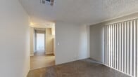 This single-floor residential unit offers a practical and comfortable layout designed for everyday living. The living area is finished with wall-to-wall carpet and features a large sliding glass door dressed with vertical blinds, allowing natural light to fill the room while providing easy access to the outdoors. A textured ceiling runs throughout the main living spaces, adding a classic touch to the interior.

The galley-style kitchen is efficiently designed with ample white cabinetry lining both sides, providing generous storage space. Light wood-style flooring runs underfoot, complementing the white appliances, including a refrigerator, electric coil range, and a ventilation hood. A window with vertical blinds at the end of the kitchen brings in additional natural light.

A hallway connects the main living space to the bedroom and bathroom. The bedroom is a well-proportioned room finished with plush carpet and features a window that lets in natural daylight. The full bathroom is clean and functional, showcasing wood-look tile flooring, a single-sink vanity with a light countertop, a toilet, and a full-size bathtub and shower combination with a white surround. Throughout the unit, neutral tones and consistent finishes create a cohesive and move-in-ready environment.