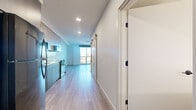 Located at 21 Boston St in Seattle's Queen Anne neighborhood, this one-bedroom, one-bathroom unit offers a thoughtfully designed layout with modern finishes throughout. Light wood-tone luxury vinyl plank flooring runs continuously across the entire space, creating a cohesive and clean aesthetic.

The open-plan kitchen and living area forms the heart of the unit. The kitchen is outfitted with two-tone wood cabinetry in light and dark finishes, a white quartz countertop, white subway tile backsplash, and stainless Whirlpool appliances including a range, over-the-range microwave, and dishwasher. A matte black faucet adds a refined contrast to the bright countertops.

A sliding barn door leads from the main living area into the bedroom, which features a large sliding glass door that fills the room with natural light and offers elevated views of the surrounding Seattle cityscape and neighborhood. The bedroom also includes a closet with built-in shelving for organized storage.

The bathroom is finished with crisp white subway tile surrounding the soaking tub and shower, a dark wood vanity with a white undermount sink, matte black fixtures, and a large backlit mirror. Recessed lighting throughout the unit completes the modern, polished feel of this well-appointed Seattle residence.