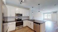 Located at 10 Willard Rd in Norwalk, Connecticut, this single-floor residence showcases a clean, contemporary design with thoughtful finishes throughout. Light wood-tone flooring runs continuously across the living areas, complementing the bright, neutral palette that gives the space an open and airy feel.

The kitchen is a standout feature, designed with white shaker-style cabinetry reaching toward the ceiling, a classic subway tile backsplash, and dark quartz countertops that provide striking contrast. A peninsula with an integrated sink and modern industrial-style pendant lighting serves as both a functional workspace and a social hub. Stainless steel appliances, including a refrigerator, electric range, microwave, and dishwasher, complete this well-equipped kitchen.

The open-concept layout connects the kitchen seamlessly to the living area, which benefits from recessed lighting and a large window that invites natural light. The bedroom offers a comfortable retreat with its own walk-in closet featuring built-in shelving, along with access to an in-unit washer and dryer. The bathroom is finished with clean white subway tile in the shower-tub surround, chrome fixtures, and a bright, understated aesthetic. Throughout, the space reflects a modern sensibility defined by clean lines, quality materials, and functional design.