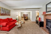 Located at 6054 SW 25th St in Topeka, Kansas, this single-floor home offers a well-organized layout designed for comfortable everyday living. The expansive living area is carpeted and open in feel, anchored by a bold brick fireplace with a wood mantle that serves as a striking focal point. The space flows naturally into a dedicated dining room, which features a contemporary chandelier, neutral-toned walls, and a glass-top dining table — ideal for gathering and entertaining. The galley-style kitchen is efficiently designed with ample cabinetry, dark countertops, black appliances including a range and refrigerator, and durable wood-look flooring. The primary bedroom is a comfortable retreat with vaulted ceiling detailing, a ceiling fan, and plush carpeting. A second bedroom provides additional sleeping quarters with a textured ceiling and soft carpet underfoot. The bathroom offers dark granite-style countertops, wood-trimmed cabinetry, and a mirrored medicine cabinet. A dedicated in-unit laundry room houses full-sized washer and dryer units with overhead shelving for added storage. Throughout the home, neutral wall tones, natural light from multiple windows, and consistent finishes create a cohesive and inviting atmosphere.