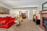 Located at 6054 SW 25th St in Topeka, Kansas, this single-floor home offers a well-organized layout designed for comfortable everyday living. The expansive living area is carpeted and open in feel, anchored by a bold brick fireplace with a wood mantle that serves as a striking focal point. The space flows naturally into a dedicated dining room, which features a contemporary chandelier, neutral-toned walls, and a glass-top dining table — ideal for gathering and entertaining. The galley-style kitchen is efficiently designed with ample cabinetry, dark countertops, black appliances including a range and refrigerator, and durable wood-look flooring. The primary bedroom is a comfortable retreat with vaulted ceiling detailing, a ceiling fan, and plush carpeting. A second bedroom provides additional sleeping quarters with a textured ceiling and soft carpet underfoot. The bathroom offers dark granite-style countertops, wood-trimmed cabinetry, and a mirrored medicine cabinet. A dedicated in-unit laundry room houses full-sized washer and dryer units with overhead shelving for added storage. Throughout the home, neutral wall tones, natural light from multiple windows, and consistent finishes create a cohesive and inviting atmosphere.