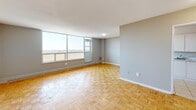 Located on the 26th floor at 2405 Finch Avenue West in Toronto, this one-bedroom, one-bathroom unit offers a well-organized layout across a single floor. The open living area is immediately welcoming, featuring warm parquet flooring in a classic basket-weave pattern that runs throughout the main spaces, adding a timeless character to the interior. Neutral grey walls complement the light tones of the flooring and create a clean, versatile canvas.

The living space is generously proportioned, benefiting from large floor-to-ceiling windows that frame sweeping open views of the Toronto skyline and surrounding treetops. Baseboard heating units run beneath the windows, ensuring year-round comfort. Natural light fills the room throughout the day, lending a bright and airy atmosphere.

The kitchen is separated from the living area, offering a functional space with white cabinetry, light tile flooring, and built-in appliances including a stove. A tiled backsplash adds a practical finishing touch to this efficient cooking area.

The bedroom is spacious and well-lit, with its own window overlooking the city, providing a calm and private retreat. The bathroom features a full-sized soaker tub with an overhead shower, framed by neutral beige ceramic wall tiles and chrome fixtures, offering a clean and classic finish throughout.