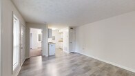 This well-organized 1-bedroom, 1-bathroom unit offers a practical and efficient single-floor layout. The living room features light-toned luxury vinyl plank flooring, crisp white walls, and a textured ceiling, creating a clean and neutral environment. A louvered closet door and built-in thermostat add functional touches to the space, while a floor vent ensures consistent climate control throughout.

The galley-style kitchen is thoughtfully designed with white cabinetry, stone-patterned countertops, a gas range, refrigerator, and dishwasher — all finished in white. Light-toned vinyl plank flooring continues through the kitchen, maintaining a cohesive aesthetic. An electrical panel is conveniently accessible within the kitchen area.

The bedroom is carpeted for added comfort and features a sliding mirrored closet with built-in shelving and hanging rods, providing ample storage. A window allows natural light to filter into the room, enhancing its warm, neutral tones. The textured ceiling is consistent throughout the unit.

The bathroom is clean and functional, featuring a full-size soaking tub with an overhead shower, a toilet, and a towel bar, all finished in white and set against wood-look flooring. The overall unit presents a move-in-ready, well-maintained space suited for efficient, comfortable living.