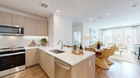 Located at 15 Artisan Dr. in Salem, NH, this thoughtfully designed 2-bedroom, 4-bathroom residence offers a bright, modern aesthetic across a well-organized single-floor layout. The open-concept kitchen and living area serves as the heart of the home, featuring light wood cabinetry, white quartz countertops, a tile backsplash, and a full suite of stainless steel appliances including a refrigerator, range, and dishwasher. A kitchen island with a stainless steel sink flows naturally into the dining and living areas, where warm hardwood flooring, recessed lighting, and large windows invite abundant natural light. The living room is an airy, welcoming space with floor-to-ceiling window treatments and access to the outdoors. Both bedrooms are generously proportioned, offering hardwood floors, ceiling fans, and large windows with ample natural light. The primary bedroom connects to a well-appointed en-suite bathroom featuring marble-style tile flooring, a floating wood vanity, and a glass-enclosed walk-in shower with elegant marble-style tile surround. Spacious walk-in closets with adjustable shelving provide excellent storage. The additional bathrooms echo the same refined, contemporary design. A hallway connects all areas cohesively, completing this polished and functional residence.