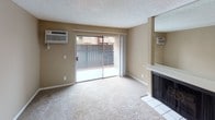 This single-floor residence offers a practical and comfortable layout with a cohesive neutral color palette throughout. The kitchen is a standout feature, showcasing rich dark cabinetry, light stone-toned countertops, a decorative tile backsplash, and warm hardwood-style flooring. A full suite of appliances, including a refrigerator and dishwasher, adds convenience, while ample upper and lower cabinet storage ensures functionality.

The living area is carpeted and centers around a fireplace, creating a cozy focal point. A large sliding glass door floods the space with natural light and provides direct access to a private patio, offering pleasant outdoor views. Wall-mounted air conditioning units are present for climate control. A large mirror above the fireplace mantle enhances the sense of space.

The bedrooms are carpeted and feature textured ceilings and neutral taupe walls. One bedroom includes a ceiling fan and a built-in shelving unit within a closet, offering excellent storage. Another bedroom benefits from a sliding window that brings in natural light.

The bathroom is clean and bright, featuring a full soaking tub with a shower, a wide dual-sink vanity with a speckled countertop, and a large mirror. Hardwood-style flooring carries through the hallway and bathroom areas, tying the space together with a consistent, warm aesthetic.