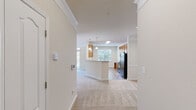 Located at 59 Summerlake Cir in Ridgeland, SC, this one-bedroom, one-bathroom residence offers a well-organized, single-floor layout designed for comfortable everyday living. The open-concept kitchen and living area forms the heart of the home, featuring warm honey-toned wood cabinetry, light countertops, and black appliances including a range, refrigerator, microwave, and dishwasher. A peninsula with a double sink adds additional workspace and casual dining potential, while pendant lighting and a skylight brighten the area. Durable wood-look flooring runs throughout the kitchen and living spaces, creating a cohesive, low-maintenance aesthetic. The spacious bedroom is finished with plush carpeting, crown molding, a ceiling fan with light fixture, and a window that lets in natural greenery views. The full bathroom includes a warm wood vanity with ample cabinet storage, a tub/shower combination, and wood-look flooring. A dedicated laundry room houses a full-size washer and dryer with wire shelving above for additional storage. The hallway connects all spaces efficiently, and a closet provides practical storage. Neutral, warm-toned walls throughout give the home a clean and inviting atmosphere.