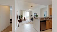 Unit 713 is a thoughtfully designed multi-bedroom residence spread across a single floor, offering a clean, contemporary aesthetic throughout. The open-concept living area is bathed in natural light, thanks to floor-to-ceiling sliding glass doors that lead to a private balcony overlooking scenic outdoor views. The living room provides a generous, comfortable layout with light tile flooring that runs seamlessly through the main areas.

The kitchen is outfitted with warm wood cabinetry, granite-style countertops, stainless steel appliances including a range and built-in microwave, and a stainless steel sink. A breakfast bar connects the kitchen to the main living space, making it ideal for both cooking and casual dining.

The residence includes multiple bedrooms, each carpeted for comfort and featuring large windows that allow ample natural light. The bedrooms offer a calm, neutral palette with ample space for furnishings.

The bathrooms are finished with light tile flooring, white vanity cabinetry, granite countertops, and large mirrors with overhead lighting, providing a clean and functional design. Overall, the unit presents a bright, modern living environment with a cohesive design language, blending practicality with comfort throughout every room.