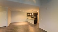 Located at 3202 W Nine Mile Rd. in Pensacola, Florida, this single-floor space offers a clean, modern aesthetic with an open-concept design that maximizes functionality and flow. The living area features rich hardwood-style flooring that extends seamlessly throughout, creating a warm and cohesive atmosphere. Recessed lighting and a track lighting system illuminate the space evenly, enhancing its bright, welcoming ambiance. The kitchen is a standout feature, showcasing dark espresso cabinetry that contrasts elegantly against light countertops and a white breakfast bar peninsula — ideal for casual dining or entertaining. Stainless steel appliances, including a microwave, range, and refrigerator, add a contemporary touch, while stylish pendant lighting above the peninsula provides both task lighting and visual appeal. Crown molding along the upper walls adds a refined architectural detail that elevates the overall design. The open sightlines between the living and kitchen areas create a sense of spaciousness, making the layout feel expansive and versatile. The neutral color palette throughout contributes to a move-in-ready environment that easily accommodates a variety of interior styles.