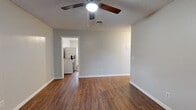 This single-floor residence offers a practical and well-organized layout, encompassing a living room, kitchen, and two bedrooms. Warm-toned wood-look flooring runs consistently throughout the entire space, lending a cohesive and inviting feel to every room.

The living room serves as the central gathering area, featuring a ceiling fan with integrated lighting and a textured ceiling. Natural light enters through a front-facing window, and a direct entry door opens into this space, making it both accessible and welcoming.

The kitchen is efficiently arranged with ample white upper and lower cabinetry, a speckled laminate countertop, an under-cabinet range hood, and a dishwasher. A window provides natural light, and the space connects openly to the rest of the unit, supporting ease of movement.

The primary bedroom offers a generous footprint, a ceiling fan, and a closet, providing functional personal space. The second bedroom is similarly appointed with wood-look flooring, a window with blinds for natural light and privacy, and neutral gray walls shared throughout the home.

Textured ceilings, clean white trim and baseboards, and a consistent neutral gray wall palette create a uniform, low-maintenance aesthetic throughout the entire residence.