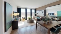 This thoughtfully designed single-floor residence blends modern aesthetics with functional living. The open-concept kitchen is a standout feature, outfitted with warm wood-grain cabinetry extending to the ceiling, white quartz countertops, a classic subway tile backsplash with under-cabinet lighting, and a full suite of stainless steel appliances including a gas range, built-in microwave, dishwasher, and refrigerator. A kitchen island provides additional prep and dining space, while light wood-plank flooring ties the area together seamlessly.

The living area is bright and welcoming, with large windows that invite an abundance of natural light and offer open views of the surrounding landscape. Rich wood-toned accent walls add warmth and depth to the space, complementing the light flooring.

The bedroom is a serene retreat, featuring plush carpeting, generous natural light from wide windows, and a calm, neutral color palette that creates a restful atmosphere.

The bathroom is spacious and well-finished, featuring large-format tile flooring, a combination soaking tub and shower with a curved curtain rod, a contemporary vanity with wood cabinetry, and contrasting dark textured accent walls that add a sophisticated touch. The overall ambiance of the residence is modern, cohesive, and refined.