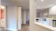 This single-floor space showcases a thoughtfully updated interior with a cohesive, contemporary aesthetic throughout. The kitchen is a standout feature, outfitted with crisp white shaker-style cabinetry extending to the ceiling, bright white quartz countertops, a stainless steel farmhouse sink, and a full suite of stainless steel appliances including a refrigerator, electric range with over-the-range microwave, and dishwasher. A subway tile backsplash adds a clean, modern touch, while recessed lighting and track lighting ensure the space is well-illuminated. The kitchen opens to the living area via a pass-through counter, creating a connected, open-concept flow ideal for entertaining.

The living area is generously proportioned, featuring light wood-look flooring, soft neutral-toned walls, and a ceiling fan with integrated lighting. Track lighting supplements the natural light that streams in through a sliding glass door, which provides direct access to a green outdoor area. The bedroom continues the light, airy palette with matching flooring, a ceiling fan, and a large window with blinds. Louvered closet doors are visible along the hallway, offering practical storage. Textured ceilings are present throughout, adding a subtle architectural detail to the overall design.