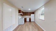 Located at 3688 Big Tree Rd in Hamburg, NY, this single-floor, one-bedroom, one-bathroom unit offers a practical and comfortable layout. The space is thoughtfully organized across five distinct areas: a living room, bedroom, kitchen, bathroom, and hallway.

The kitchen is a functional L-shaped space featuring rich, dark wood cabinetry with ample upper and lower storage, a white electric range, dishwasher, and full-size refrigerator. Light wood-look flooring runs throughout the kitchen, which also benefits from a large window that brings in natural light and views of the surrounding greenery.

The living room is a generously proportioned open area finished with neutral beige carpet and warm-toned walls. A wide window frames views of the backyard, filling the room with natural light and connecting the interior to the outdoors. A hallway transitions seamlessly between the living spaces.

The bedroom is a well-sized, private room with the same plush carpeting, neutral walls, and a window that allows natural light to filter in.

The bathroom features clean white subway tile wainscoting, a combined tub and shower unit, and a toilet, offering a straightforward and functional design. The overall ambiance of the unit is clean, practical, and move-in ready.