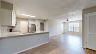 Located at 3595 Misty Oak Drive in Melbourne, FL, this single-floor, 2-bedroom, 2-bathroom residence offers a well-designed layout with modern finishes throughout. The heart of the home is an open-concept living, dining, and kitchen area unified by warm wood-look luxury vinyl flooring and textured ceilings. The kitchen is a standout feature, showcasing white shaker cabinetry, a light gray subway tile backsplash, granite countertops with an extended peninsula that doubles as a breakfast bar, and a full suite of stainless steel appliances including a range, microwave, dishwasher, and refrigerator. The living area is bright and airy, benefiting from natural light through a large window and a ceiling fan overhead. Both bedrooms are generously proportioned, each with ceiling fans, wood-look flooring, neutral gray walls, and ample closet space. The bathrooms are clean and functional, featuring tub-shower combinations and vanities with stone-look countertops. Additional highlights include a dedicated laundry area, a utility room, a balcony, and multiple closets for storage. The consistent neutral color palette and updated finishes create a cohesive, move-in-ready ambiance throughout the entire space.