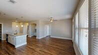 The Cassidy is a well-appointed one-bedroom, one-bathroom unit located in Cypress, TX, offering a thoughtfully designed single-level layout. Rich, dark hardwood-style flooring runs throughout the entire space, providing a warm and cohesive aesthetic from room to room.

The open-concept living and dining area is generously sized, bathed in natural light from multiple large windows dressed with white blinds. A ceiling fan adds both function and style to the space. The layout flows seamlessly into the kitchen, which serves as a central hub of the home.

The kitchen is equipped with stainless steel appliances, including a refrigerator, electric range, and microwave. White cabinetry with sleek hardware pairs with granite countertops and a tile backsplash. A peninsula island with an undermount sink and pendant lighting above offers additional prep space and casual seating. An adjacent walk-in pantry with built-in shelving provides ample storage.

A charming arched alcove off the main living area houses a built-in desk with cabinetry above, creating a dedicated workspace or study nook. The bathroom features a full soaking tub, a vanity with a white countertop, and hardwood-style flooring that maintains the consistent design language found throughout the unit. The bedroom offers a comfortable and private retreat to complete this functional and attractive floor plan.