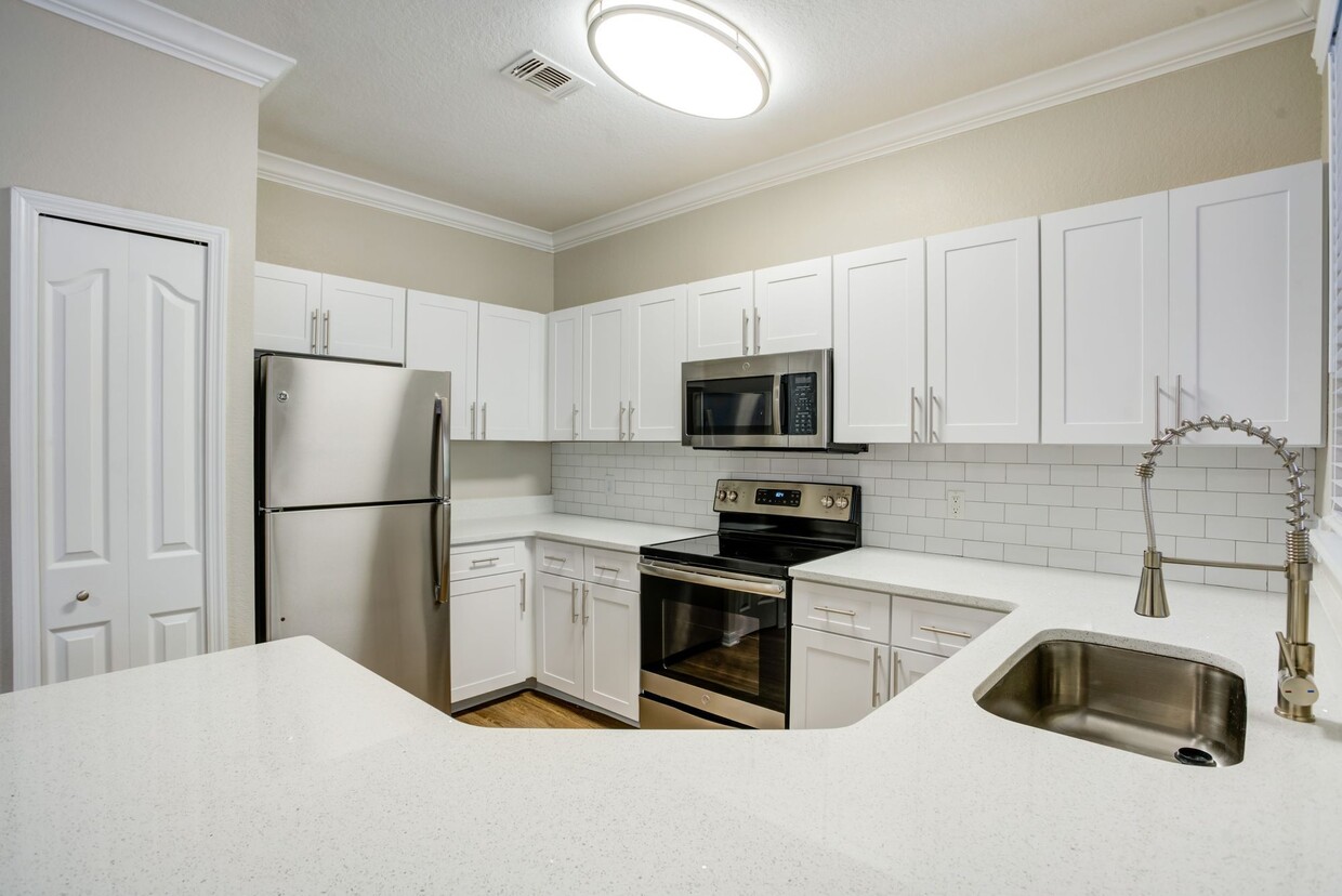 Image of a kitchen with wrap around quartz counters and a ceramic backsplash. - Amara at Metro West