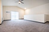 Located at 815 Commons Cir in Plover, Wisconsin, this two-story home offers a practical and comfortable layout across two floors. The main living level hosts an open-concept kitchen and living room, where rich dark-stained cabinetry, granite-look countertops, and stainless steel appliances—including a range, microwave, and refrigerator—define a functional kitchen. The living area features plush carpeting, vaulted ceilings, a ceiling fan, and a sliding glass door that opens to a private patio, allowing ample natural light to fill the space. A dedicated laundry room with a full-size front-loading washer and dryer adds everyday convenience on the same floor. Two carpeted bedrooms provide comfortable retreats; the primary bedroom is generously sized with vaulted ceilings and a window overlooking the surroundings. The full bathroom includes a soaking tub/shower combination and wood-look flooring. Two closets offer additional storage throughout. Carpeted staircases with clean white railings connect the floors. The attached garage, accessible from the lower level, provides secure parking and extra storage space. Neutral warm tones and consistent finishes throughout give the home a cohesive, move-in-ready feel.