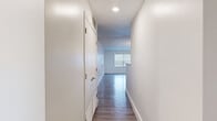 This single-floor unit offers a practical and well-organized layout across two bedrooms and two bathrooms. The interior is finished with a clean, neutral palette of white walls and white trim throughout, lending the space a bright and cohesive feel.

A central hallway, lit by recessed lighting, connects the main living areas and provides access to both bedrooms and bathrooms. The hallway features wood-style flooring that extends into the kitchen and main living areas, while the bedrooms are carpeted for added comfort. A dedicated closet off the hallway provides convenient additional storage.

The kitchen is equipped with stainless steel appliances, including a refrigerator, as well as white cabinetry and a double stainless steel sink. An adjacent laundry area accommodates a washer and dryer side by side, adding to the unit's functionality.

Both bedrooms are carpeted and feature windows with blinds that allow natural light to filter in. The primary bedroom includes a walk-in closet outfitted with wire shelving. Each bathroom includes a shower-tub combination with brushed nickel fixtures and wood-style flooring, maintaining a consistent design aesthetic throughout the unit.