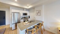 Located in Edmonton's Admiral Girouard Street community, this thoughtfully designed one-bedroom, one-bathroom unit offers a functional and modern living experience. The open-concept layout seamlessly connects the kitchen and dining area, creating an efficient and welcoming living space. The kitchen is outfitted with stainless steel appliances — including a full-size refrigerator, electric range, and built-in microwave — complemented by crisp white cabinetry, a classic subway tile backsplash, and a peninsula with a stone countertop and bar seating, ideal for casual dining. Light hardwood-style flooring runs throughout, enhancing the bright, airy feel of the interior. The bedroom is a comfortable retreat, featuring a large window with sheer curtains that invite natural light and offer views of the surrounding neighbourhood. A dedicated closet provides practical storage. The bathroom is clean and functional, finished with neutral tones and a full tub-shower combination. A private balcony, accessible through a glass-paned door, extends the living space outdoors and overlooks the residential streetscape. Recessed lighting and a wall-mounted climate control unit round out the practical features of this well-appointed unit.