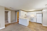 Located in Everett, WA, this one-bedroom, one-bathroom residence offers a thoughtfully designed single-floor layout. The kitchen is a standout feature, showcasing white shaker-style cabinetry, a classic subway tile backsplash, light countertops, and wood-look flooring. A central kitchen island provides additional prep and storage space, while white appliances — including a range, dishwasher, and refrigerator — complete the functional setup. An adjacent dining area features a stylish chandelier overhead.

The living room is carpeted and anchored by a white brick fireplace, adding warmth and character to the space. Sliding glass doors open to a private balcony, allowing natural light to fill the room and providing outdoor views.

The bedroom is a comfortable size, featuring plush carpet, a window with neighborhood views, and a dedicated closet with a hanging rod for organized storage. The bathroom is finished with wood-look flooring, a vanity with light countertops and modern hardware, and a full tub-shower combination. Built-in shelving adds practical storage within the bathroom area.

Neutral wall tones and consistent flooring materials throughout give this residence a cohesive, move-in-ready appeal.