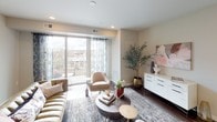 This thoughtfully designed single-floor residence offers a seamless blend of modern aesthetics and functional living. The open-concept living area serves as the heart of the home, featuring rich hardwood flooring, recessed lighting, and floor-to-ceiling sliding glass doors that lead to a private balcony, filling the space with abundant natural light and offering views of the surrounding neighborhood.

The chef's kitchen is a standout feature, appointed with granite countertops, a generous island with pendant lighting, stainless steel appliances including a gas range and French door refrigerator, sleek white cabinetry extending to the ceiling, and a classic subway tile backsplash. Hardwood floors continue throughout the kitchen, reinforcing the cohesive design.

The primary bedroom is generously sized with a ceiling fan, large windows dressed in sheer curtains, and direct access to a well-equipped en-suite bathroom featuring both a soaking tub and a separate glass-enclosed walk-in shower, all finished in clean white tile. A second bedroom offers comfortable proportions with a ceiling fan and ample natural light. Additional bathrooms include a tub-shower combination with white subway tile and a conveniently located powder room with wood-look tile flooring and dark vanity cabinetry. Neutral tones and clean lines are carried throughout, creating a refined and cohesive living environment.