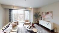 This thoughtfully designed single-floor residence offers a seamless blend of modern aesthetics and functional living. The open-concept living area serves as the heart of the home, featuring rich hardwood flooring, recessed lighting, and floor-to-ceiling sliding glass doors that lead to a private balcony, filling the space with abundant natural light and offering views of the surrounding neighborhood.

The chef's kitchen is a standout feature, appointed with granite countertops, a generous island with pendant lighting, stainless steel appliances including a gas range and French door refrigerator, sleek white cabinetry extending to the ceiling, and a classic subway tile backsplash. Hardwood floors continue throughout the kitchen, reinforcing the cohesive design.

The primary bedroom is generously sized with a ceiling fan, large windows dressed in sheer curtains, and direct access to a well-equipped en-suite bathroom featuring both a soaking tub and a separate glass-enclosed walk-in shower, all finished in clean white tile. A second bedroom offers comfortable proportions with a ceiling fan and ample natural light. Additional bathrooms include a tub-shower combination with white subway tile and a conveniently located powder room with wood-look tile flooring and dark vanity cabinetry. Neutral tones and clean lines are carried throughout, creating a refined and cohesive living environment.