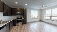 This well-appointed single-floor residence offers a thoughtfully designed layout with a clean, contemporary aesthetic throughout. The open-concept kitchen is a functional centerpiece, featuring dark espresso cabinetry, light granite-style countertops, and a full suite of stainless steel appliances including a refrigerator, electric range, over-the-range microwave, and dishwasher. Light wood-look luxury vinyl plank flooring runs throughout the main living areas, complementing the neutral white walls and recessed lighting for a bright, cohesive feel. The kitchen flows seamlessly into the living and dining area, which is bathed in natural light from large windows with blinds and equipped with a ceiling fan. The bedrooms offer plush carpeting, generous closet space with wire shelving, ceiling fans, and windows that provide views of the surrounding area. The bathrooms are finished with dark cabinetry, marble-style countertops, and light LVP flooring. One bathroom includes a walk-in shower, while the other features a full tub-shower combination with built-in shelving. A dedicated in-unit laundry area accommodates a full-size washer and dryer with overhead shelving, adding everyday convenience. The space presents a modern, move-in-ready environment with consistent finishes throughout.