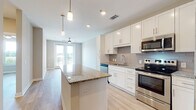 Located at 1321 Starling Dr in Henrico, Virginia, this single-floor residence offers a thoughtfully designed layout with modern finishes throughout. The kitchen serves as the centerpiece of the living area, showcasing crisp white shaker cabinetry, granite countertops, a large central island with built-in outlets, and a full suite of stainless steel appliances including a range, microwave, dishwasher, and refrigerator. A neutral tile backsplash and light wood-look flooring complete the polished aesthetic. Pendant lighting over the island and recessed ceiling lights provide layered illumination, while a ceiling fan near the French doors leading to the outdoor space promotes comfortable airflow. The living area benefits from abundant natural light streaming through the glass doors. The bedrooms are well-proportioned, featuring the same light hardwood-style flooring, ceiling fans, and windows with blinds that invite natural light while maintaining privacy. The bathroom is finished with marble-look tile flooring, a granite-topped white vanity with an undermount sink, a large wall mirror, and a full tub-shower combo with white tile surround. The overall aesthetic is clean, contemporary, and cohesive, offering a move-in-ready living experience.