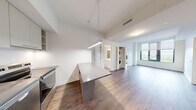 This well-designed 4-bedroom, 2-bathroom unit offers a thoughtfully laid-out single-floor plan with a clean, contemporary aesthetic throughout. Rich hardwood flooring flows seamlessly from room to room, complemented by crisp white walls and abundant natural light.

The open-concept kitchen is a standout feature, showcasing grey flat-panel cabinetry extending to the ceiling, stainless steel appliances including a full-size refrigerator, electric range, and dishwasher, along with a generous island with a grey countertop that doubles as an informal dining surface. A linear pendant light fixture overhead adds a modern touch. The kitchen connects naturally to the living area, which benefits from large windows framing expansive treetop and city skyline views.

A central hallway connects the four bedrooms, each offering hardwood floors and windows for natural light. The primary bedroom features dual closets and direct access to one of the two bathrooms. Both bathrooms are finished with large-format neutral tiles, soaker tubs with tiled surrounds, white vanities with quartz countertops, and recessed lighting. In-unit stacked laundry is also conveniently located within the layout. The overall ambiance is bright, modern, and functional, making efficient use of every square foot.