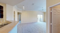 This single-floor, one-bedroom, two-bathroom residence offers a thoughtfully designed layout that maximizes its compact footprint. The open-concept living area is a standout feature, boasting vaulted ceilings with crown molding, plush neutral carpeting, and a ceiling fan that enhances airflow throughout the space. Track lighting illuminates the living area, which also features a distinctive arched built-in shelving unit, adding architectural character. A sliding glass door leads directly to a private balcony, filling the room with natural light and providing outdoor views.

The kitchen is positioned adjacent to the living area and features dark espresso cabinetry, a breakfast bar countertop, tile flooring, black appliances including a refrigerator, range, and microwave, and a double sink. A closet near the kitchen entrance provides convenient additional storage.

The bedroom is a comfortable size, with carpeted flooring, a large window allowing natural light, and neutral wall tones. The two bathrooms include tile flooring, dark vanity cabinetry with light countertops, a large mirror, and a tub-shower combination with tile surround. A hallway connects the rooms, contributing to an efficient and functional overall flow throughout the residence.