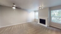 This well-appointed single-floor residence in Bothell, Washington offers a thoughtfully designed layout with a clean, neutral aesthetic throughout. The living room serves as the heart of the home, featuring plush wall-to-wall carpeting, a ceiling fan with light fixture, track lighting, and a classic white-framed fireplace that adds warmth and character to the space. A window allows natural light to fill the room, while a pass-through window connects seamlessly to the kitchen, enhancing the open feel.

The kitchen is efficiently designed with crisp white cabinetry, light countertops, stainless steel appliances including a refrigerator and electric range with hood, and a peninsula that doubles as a breakfast bar. Wood-look flooring ties the space together with a modern touch.

The bedrooms are generously sized, finished with soft carpeting and offering views of the surrounding neighborhood through large windows fitted with blinds. Baseboard heating ensures comfort year-round.

Two bathrooms provide functional convenience, each featuring white vanity cabinetry, large mirrors, and wood-look tile flooring. One bathroom includes a soaking tub, while the other offers a private water closet. The home's cohesive neutral palette and practical layout make it an inviting and versatile living space.