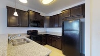 Located at 308 East 2nd Street in Hummelstown, Pennsylvania, this single-floor residence offers a thoughtfully designed living space. The kitchen serves as a standout feature, showcasing rich, dark espresso-toned cabinetry that extends from floor to ceiling, providing generous storage throughout. Complementing the cabinetry are light granite countertops with subtle flecks of color, creating an elegant contrast that enhances the overall aesthetic. The kitchen is fully equipped with a suite of black appliances, including a refrigerator, electric range, and built-in microwave, seamlessly integrated into the cabinetry for a cohesive, polished look. The layout is efficiently designed in an L-shape, maximizing workspace and functionality. A peninsula or counter overhang is also present, offering additional prep space or the potential for casual seating. The flooring throughout the kitchen is light in tone, further balancing the darker upper elements and contributing to a bright, welcoming atmosphere. Overhead, a contemporary flush-mount light fixture provides ample illumination. This residence combines practical design with quality finishes, making it a comfortable and functional home in the heart of Hummelstown, PA.