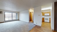 This single-floor unit is thoughtfully laid out to maximize functionality and comfort. The open-concept living area is anchored by neutral carpet and transitions seamlessly to hardwood-style flooring near the kitchen and entryway. A large sliding glass door floods the living space with natural light and provides direct access to a private balcony with outdoor views. A baseboard heating system runs along the perimeter, supplemented by wall-mounted A/C units for year-round climate control. The textured ceilings are consistent throughout the main living areas.

The kitchen features warm oak cabinetry, light laminate countertops in an L-shaped configuration, a double stainless steel sink, and white appliances including an electric range with overhead microwave. The hardwood-style flooring continues through this space, adding a cohesive feel.

The bedrooms are generously sized, each with plush carpet, baseboard heating, and windows that bring in natural light. One bedroom includes a sliding wood-panel closet. The unit offers two bathrooms: one with beige tile surrounding a full soaking tub, and a second with dark tile surround and hardwood-style flooring, providing versatile options for residents.