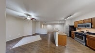 Located at 6885 W Lone Mountain Rd in Las Vegas, NV, this well-appointed residence offers four bedrooms and two full bathrooms across a single-floor layout. The open-concept living and dining area is anchored by rich wood-style flooring and a ceiling fan, creating a comfortable, connected atmosphere. A central kitchen island with granite countertops bridges the living space and the kitchen, which is outfitted with warm wood cabinetry, stainless steel appliances including a gas range, built-in microwave, and refrigerator. A chandelier over the adjacent dining nook adds an elegant finishing touch, while vertical blinds allow for flexible natural light control. The bedrooms feature the same durable wood-style flooring and are served by six-panel doors and closets with built-in rods for ample storage. Both bathrooms are consistently finished with warm wood vanities, granite countertops, large mirrors with overhead lighting, and tub-shower combinations with clean white tile surrounds. The neutral, warm-toned color palette used throughout the home lends a cohesive and inviting ambiance, making this Las Vegas residence a practical yet comfortable place to call home.