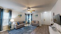 Located at 204 Hawthorne Groves Blvd in Orlando, FL, this single-floor, 2-bedroom, 2-bathroom home offers a well-designed layout that maximizes functionality and comfort. The open-concept living, dining, and kitchen area forms the heart of the home, featuring warm wood-look flooring, neutral walls, and a ceiling fan that anchors the space. Large windows dressed with elegant draping curtains allow natural light to fill the living room, which offers ample room for seating and entertaining. The galley-style kitchen is equipped with light wood cabinetry, stainless steel appliances including a refrigerator and range, a double sink, and a dishwasher — all oriented for efficient workflow. A dedicated dining area sits conveniently adjacent to the kitchen. Both bedrooms are carpeted and offer a calm, restful atmosphere, with the primary bedroom featuring a walk-in closet with built-in wire shelving. The home includes five closets total, providing exceptional storage throughout. The bathrooms feature wood-toned vanity cabinetry with well-lit mirrors. A dedicated laundry area adds everyday convenience. The clean, neutral palette and cohesive design make this a highly functional and inviting home.