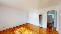Located at 1522 Tijeras Ave NE in Albuquerque, New Mexico, this single-story one-bedroom, one-bathroom home offers a straightforward and functional layout across a compact footprint. Warm-toned hardwood floors run throughout the living room and bedroom, lending a cohesive and inviting feel to the space. The living room is bright and open, benefiting from a large window fitted with vertical blinds that allow natural light to fill the room, alongside a secondary smaller window near the entry door. The bedroom continues the hardwood flooring and features its own window with blinds, offering natural light and a connection to the outdoors. A closet provides dedicated storage within the bedroom. The kitchen is tiled in neutral tones and is equipped with white cabinetry, a gas range, a double-basin stainless steel sink, and a water heater tucked into the corner. A window in the kitchen adds ventilation and light. The bathroom includes a full tub and shower combination with white tile surround, a floral shower curtain, and a dark wood vanity with an integrated sink. A small window above the tub provides natural light. A hallway connects the rooms efficiently, completing this well-organized and practical single-floor layout.