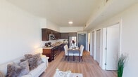 This well-designed single-floor residence offers a clean, contemporary aesthetic with an open-concept layout that seamlessly connects the living, dining, and kitchen areas. Light wood-tone flooring flows throughout the main living spaces, complementing the crisp white walls and creating a bright, airy atmosphere. The living area is bathed in natural light from a large sliding glass door that opens to an outdoor view, enhancing the sense of openness and bringing the outdoors in.

The kitchen is outfitted with rich dark cabinetry, granite countertops, a white subway tile backsplash, and a full suite of stainless steel appliances, including a refrigerator, range, microwave, and dishwasher. Ample cabinet storage extends to the ceiling, maximizing functionality. The adjacent dining area provides a dedicated space for entertaining.

Two bedrooms offer comfortable retreats, each featuring wood-tone flooring and windows that allow natural light to filter in. The primary bedroom includes an en-suite bathroom, while a second full bathroom serves the rest of the unit. Both bathrooms are finished with tile flooring, granite vanity countertops, dark cabinetry, and a bathtub with shower. Closet space is well incorporated throughout, ensuring practical storage solutions across the entire residence.