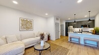 Located at 20021 Chad Hittle Dr in Westfield, Indiana, this well-appointed one-bedroom, one-bathroom unit offers a smart, modern layout across a single floor. Light wood flooring runs throughout, creating a cohesive and bright aesthetic enhanced by recessed lighting and crisp white walls.

The open-concept living area connects seamlessly to the kitchen, providing an airy, functional flow. The living room features a large sliding glass door with floor-to-ceiling curtains, allowing abundant natural light to fill the space. The kitchen is a standout, equipped with slate-gray shaker cabinets, white quartz countertops, a classic subway tile backsplash, stainless steel appliances, and a peninsula with pendant lighting and seating — ideal for casual dining or entertaining.

The bedroom is a comfortable retreat featuring a ceiling fan with light fixture, a natural light-filled window with drape curtains, and ample room for furnishings. The full bathroom includes a gray vanity with undermount sink, tile-surround bathtub and shower combo, and clean, modern finishes.

A dedicated laundry area houses a stacked washer and dryer unit, adding practical convenience. The entry area provides additional functional space, completing this efficiently designed home.