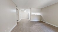 Located at 1498 Brookside Ave in Redlands, CA, this single-floor, one-bedroom, one-bathroom unit offers a functional and well-organized layout. The open-concept living and kitchen area is finished with durable wood-look vinyl flooring and neutral beige tones throughout, creating a clean, cohesive aesthetic. A ceiling fan anchors the living area, which flows naturally into the kitchen via a pass-through counter with a built-in sink — ideal for both everyday living and casual entertaining. The galley-style kitchen features white shaker cabinetry, a gas range, refrigerator, and light-colored countertops, all illuminated by recessed lighting. A hallway with a built-in white cabinet provides additional storage and leads to the private bedroom. The bedroom is carpeted for comfort and includes a ceiling fan, a window that brings in natural light and views of surrounding greenery, and access to a dedicated walk-in closet with built-in shelving and hanging rods. The bathroom is conveniently positioned off the hallway. Throughout the unit, textured ceilings, crisp white trim, and consistent neutral finishes contribute to a tidy, move-in-ready atmosphere well-suited for comfortable single-occupant living.