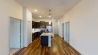 This single-floor residence presents a thoughtfully designed layout with a seamless blend of modern finishes and functional living spaces. The open-concept kitchen serves as a central highlight, featuring rich dark cabinetry extending to the ceiling, a tile backsplash, and a full suite of stainless steel appliances including a refrigerator, range, microwave, and dishwasher. A generous island with granite countertops provides additional workspace and casual seating, illuminated by stylish pendant lighting overhead. Rich hardwood-style flooring flows throughout the main living areas, complementing the neutral white walls and creating a warm, contemporary aesthetic.

The living area is bright and inviting, anchored by a ceiling fan and French doors that invite natural light and outdoor views. Bedrooms are carpeted for comfort and each features dual windows with blinds, allowing ample natural light while maintaining privacy. The bathrooms are well-appointed with dark vanity cabinetry, granite countertops, large mirrors, hardwood-style flooring, and a soaking tub with marble-style tile surround. A dedicated laundry area accommodates a full-size side-by-side washer and dryer, adding everyday convenience to this well-finished residence.