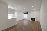Located in the vibrant West Hollywood neighborhood of Los Angeles, this single-story residence at 1440 N Alta Vista Blvd showcases a clean, modern design throughout. The open-concept living area is anchored by warm wood-look flooring, crisp white walls, and recessed lighting, creating a bright and welcoming atmosphere. A sleek, white-surround fireplace serves as a focal point in the main living space, complemented by natural light filtering through windows fitted with blackout roller shades.

The galley-style kitchen is well-appointed with high-gloss white cabinetry, white quartz countertops, large-format tile flooring, and a full suite of stainless steel appliances including a gas range, built-in microwave, refrigerator, and dishwasher — offering both style and functionality.

The bedrooms continue the home's minimalist aesthetic, featuring the same wood-look flooring, recessed lighting, and generous windows. One bedroom includes a mirrored sliding-door closet with built-in shelving, providing ample storage.

The bathroom is finished in warm beige tile and features a soaking tub with a glass-paneled shower surround, a wall-mounted toilet, and a floating vanity, lending a spa-like quality to the space. Throughout, the consistent use of neutral tones and contemporary finishes creates a cohesive and refined living environment.