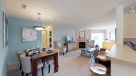 This single-floor residence offers a thoughtfully designed layout that balances comfort and functionality across its key living areas. The open-plan living and dining space is immediately welcoming, featuring soft carpet flooring, neutral tones, and a standout teal accent wall in the dining area. A pendant light fixture anchors the dining space, which comfortably accommodates a full dining table and chairs. The living room centers around a tiled fireplace flanked by a sliding glass door that invites natural light and outdoor views, creating a bright and airy atmosphere.

The kitchen is efficiently laid out with light wood cabinetry, white appliances including a refrigerator, stove, and over-range microwave, and a peninsula counter with bar seating. A breakfast nook with a window provides an additional casual dining option.

The primary bedroom is a serene retreat, featuring multiple windows with garden views, plush carpet, and elegant drapery. The second bedroom offers flexible use with ample natural light and carpeted flooring. Both bathrooms are finished with light wood vanity cabinetry, white countertops, and tile flooring. A shared hallway connects the sleeping quarters to the main living areas, completing this cohesive and comfortable residence.