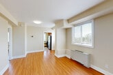 Located in the Chevy Chase neighborhood of Washington, DC, this one-bedroom, one-bathroom residence on Kanawha Street NW offers a well-organized and functional layout across a single floor. Warm hardwood-style flooring flows throughout the living spaces, complementing the neutral, light beige walls that create a bright and inviting ambiance.

The living room is an open, airy space with natural light filtering through large windows fitted with blinds, offering pleasant outdoor views. A wall-mounted heating unit ensures year-round comfort. The room connects seamlessly to the rest of the unit, providing a practical and cohesive flow.

The kitchen is efficiently designed with rich wood cabinetry, granite countertops, a stainless steel sink, and a full suite of stainless steel appliances including a refrigerator, gas range, and microwave. A window above the counter adds natural light to this well-appointed space.

The bedroom is a comfortable, well-lit retreat featuring two windows with outdoor views, hardwood-style flooring, and a mirrored closet. Two additional closets throughout the unit provide ample storage. The bathroom is finished with neutral tile, a glass-enclosed walk-in shower, a vanity with sink, and a window for ventilation and natural light.