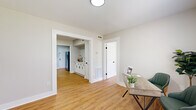 This efficiently designed single-floor home offers a thoughtful layout across two bedrooms, two office spaces, a kitchen, and a full bathroom. Warm hardwood-style flooring runs consistently throughout the space, creating a cohesive and inviting atmosphere. Neutral light gray walls and crisp white trim contribute to a clean, modern aesthetic.

The kitchen is a standout feature, showcasing white shaker-style cabinetry with matte black hardware, bright white countertops, a farmhouse-style sink, and a gray subway tile backsplash. Stainless steel appliances, including a dishwasher, range, and over-the-range microwave, complete this well-appointed cooking space. A window allows natural light to brighten the room.

The bedrooms are comfortably sized, with the primary bedroom benefiting from multiple windows offering outdoor views and a ceiling fan for added comfort. The second bedroom mirrors this bright, airy quality. Both office spaces are versatile and naturally lit, ideal for remote work or flexible use.

The bathroom is clean and functional, featuring wood-style flooring consistent with the rest of the home and a window for natural ventilation. Throughout the space, white panel doors with black hardware add a consistent design touch that ties the modern farmhouse aesthetic together seamlessly.