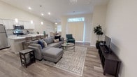 This single-story home features an open-concept design that seamlessly connects the living, dining, and kitchen areas. The living room is generously sized, highlighted by vaulted ceilings, wood-look flooring, and a large sliding glass door fitted with vertical blinds that brings in ample natural light. Ceiling fans are present throughout the home, adding both function and style.

The kitchen is equipped with white shaker-style cabinetry, granite countertops, and stainless steel appliances, including a refrigerator, range, and microwave. A breakfast bar provides additional seating alongside the dedicated dining area, which features a window and ceiling fan. A separate formal dining room accommodates a full-sized dining table, making it ideal for gatherings.

The bedrooms are carpeted for comfort, each with ceiling fans and windows offering natural light. The primary bedroom includes an attached bathroom with a granite-topped vanity and a walk-in shower. A secondary bathroom features a granite vanity and a shower-tub combination. Both bathrooms are finished with wood-look tile flooring and white cabinetry, maintaining a consistent, cohesive aesthetic throughout the home.