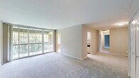 Located at 3900 Blackburn Ln in Burtonsville, MD, this well-appointed 2-bedroom, 2-bathroom residence spans a single floor and offers a practical, comfortable layout. The living room is a standout feature, with plush carpeting and a large sliding glass door that opens to a private balcony, flooding the space with natural light and offering lush, tree-lined outdoor views. The galley-style kitchen is efficiently designed with white shaker cabinets, dark granite-look countertops, light wood-look flooring, stainless steel appliances including a gas range and refrigerator, and a window that brings in additional natural light. A hallway connects the main living areas to the private quarters. Both bedrooms feature soft carpeting, neutral-toned walls, and windows with blinds that let in natural light. The spacious primary bedroom includes a closet with bifold doors, while the second bedroom is well-sized and equally comfortable. Each bathroom is finished with clean, white square tile surrounding the tub and shower areas, with the second bathroom featuring warm-toned bronze hardware. A dedicated closet and hallway complete the thoughtfully arranged floor plan of this Burtonsville residence.